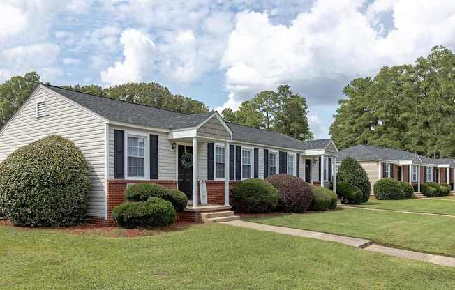 A row of houses with green lawns and trees in the background.