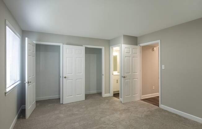 a bedroom with three doors and a carpeted floor