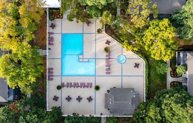 An aerial view of a pool surrounded by trees and a building.