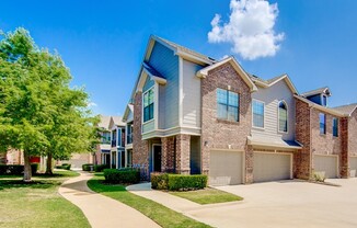 View of Building Exterior, Showing Landscaping and Private Attached Garages at Enclave on Golden Triangle Apartments