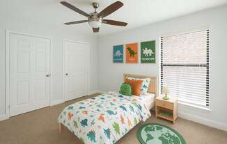 A bedroom with a bed, a ceiling fan, and a carpet with a map of the world on it.