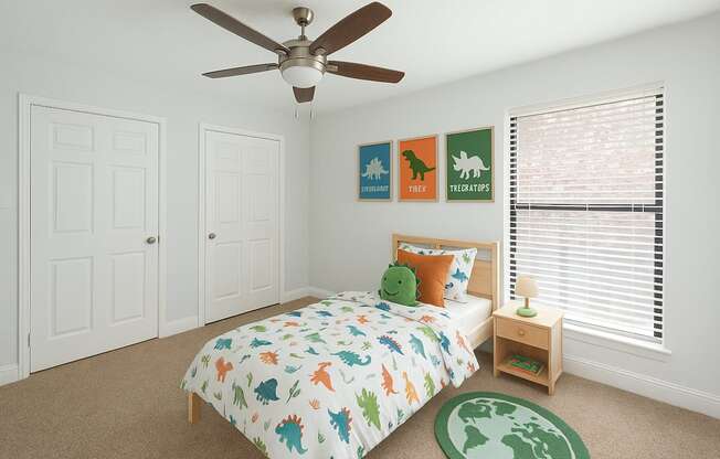 A bedroom with a bed, a ceiling fan, and a carpet with a map of the world on it.