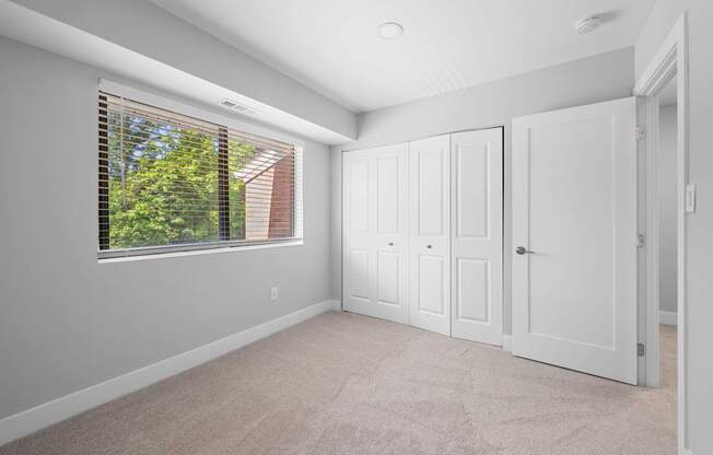 an empty bedroom with a large window and white doors