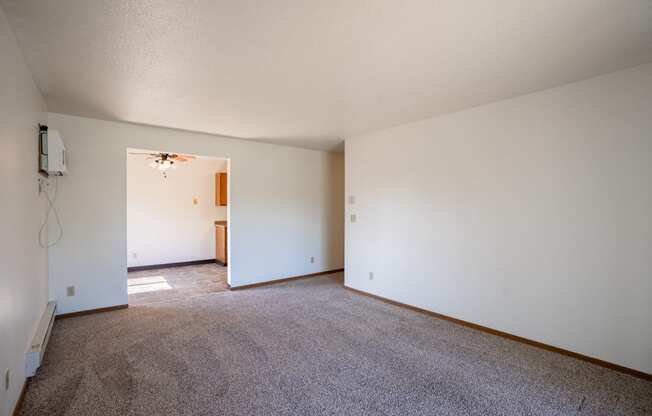 an empty living room with carpet and white walls. Fargo, ND Southview Village Apartments