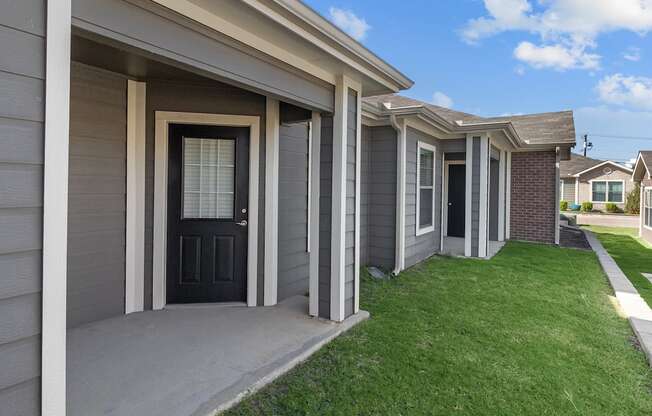 a home with a black door and a sidewalk in front of it