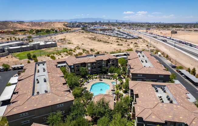 an aerial view of a building with a pool in the foreground and the desert in the background