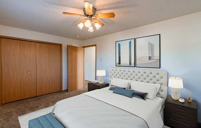 a bedroom with a large bed and a ceiling fan. Fargo, ND Sunwood Apartments
