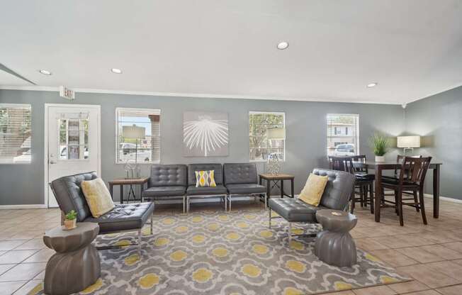 A grey sofa with yellow pillows is in the middle of a room with a grey carpet.