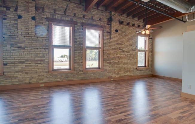 A room with wooden floors and a brick wall.