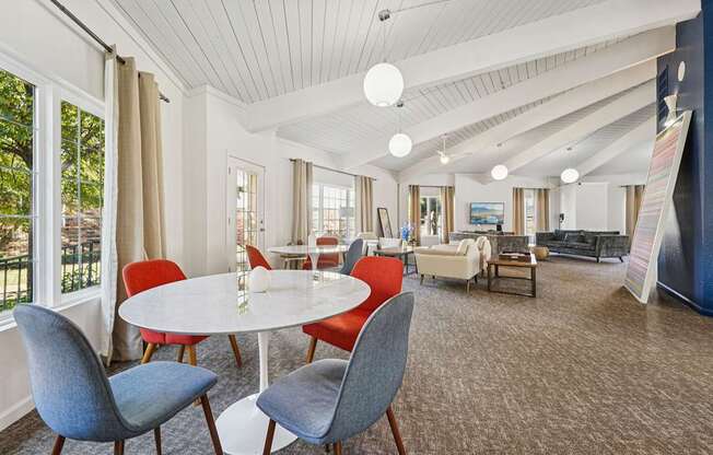 A white round table with four chairs around it in a room with a white ceiling.