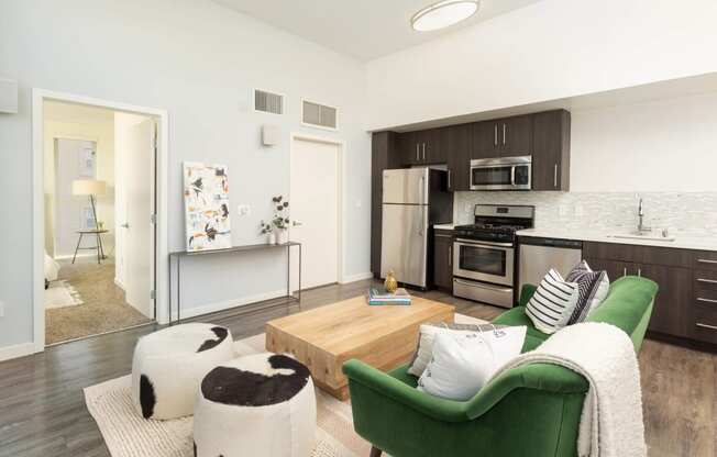 a living area with a couch coffee table and a kitchen in the background