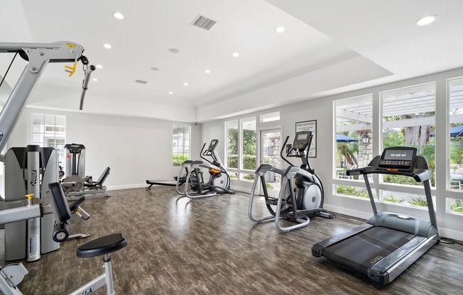 a gym with treadmills and other exercise equipment on a wood floor