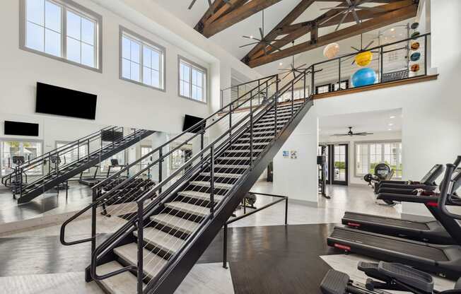 a spiral staircase in a gym with treadmills and chairs