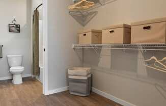 a bathroom with a toilet and a closet with boxes on the wall and a basket