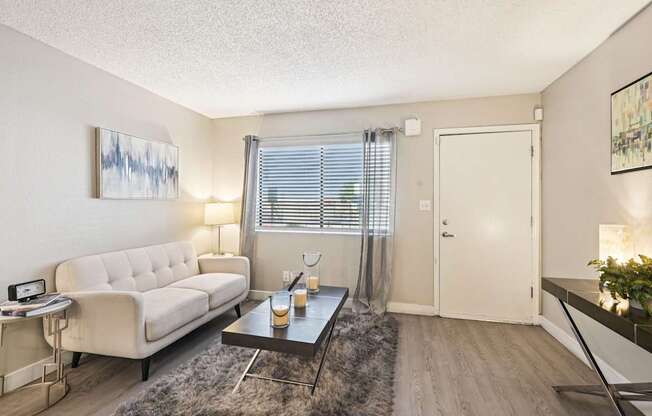 A living room with a white couch, a coffee table, and a painting on the wall.
