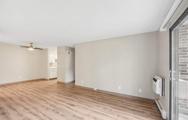 the living room of an apartment with wood flooring and a large window