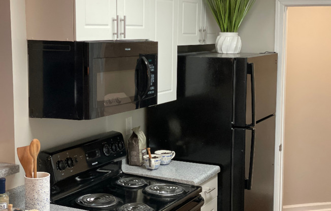 Kitchen with black appliances and white cabinets | Aqua at Sandy Springs | Sandy Springs Apartments