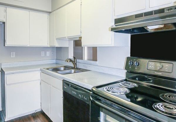 an empty kitchen with white cabinets and black appliances