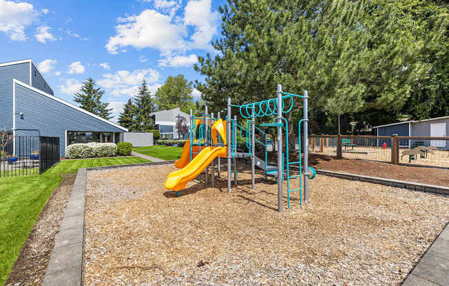A playground with a yellow slide and a blue structure.