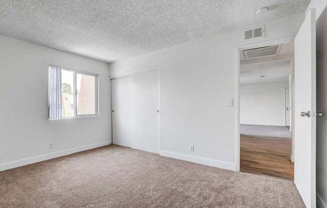 A room with a carpeted floor and a window with blinds.