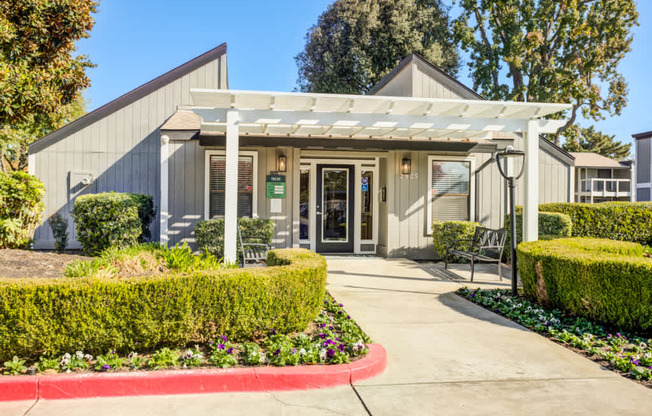 A building with a white canopy and a red border around the bushes.