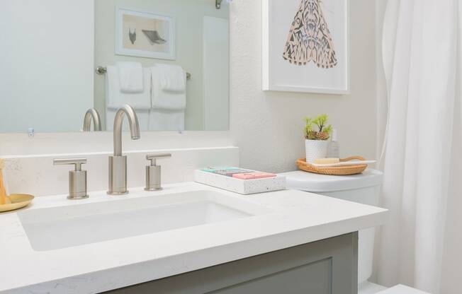 a small bathroom with a gray vanity and a white shower curtain