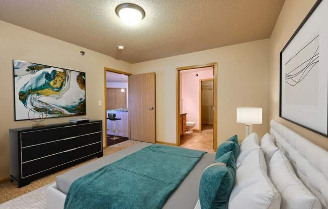 a master bedroom with a bed and a tv. Fargo, ND East Bridge Apartments