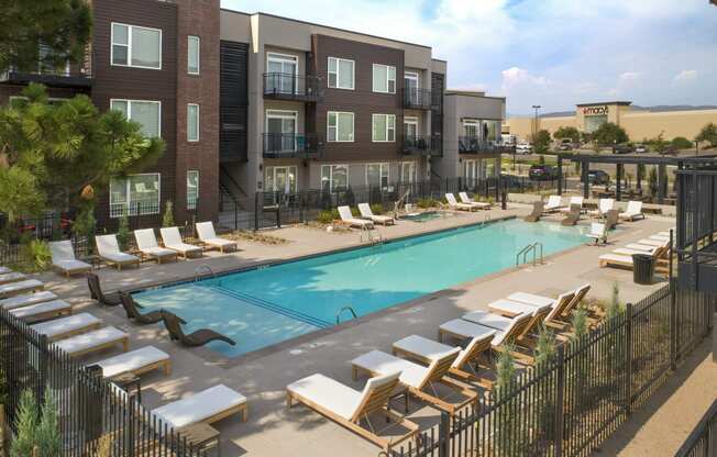 a swimming pool with lounge chairs in front of an apartment building