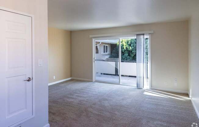 an empty living room with sliding glass doors to a patio