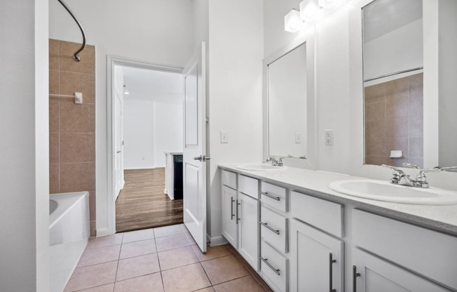 a bathroom with white cabinets and a large mirror and a tub