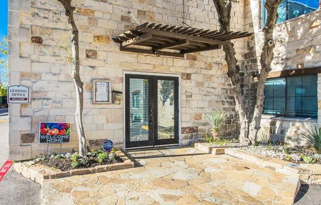 A stone building with a glass door and a leasing sign.