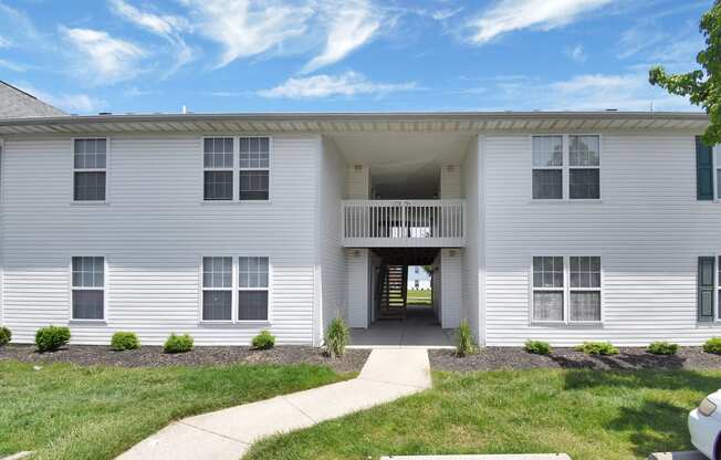 a white building with a balcony and grassy area