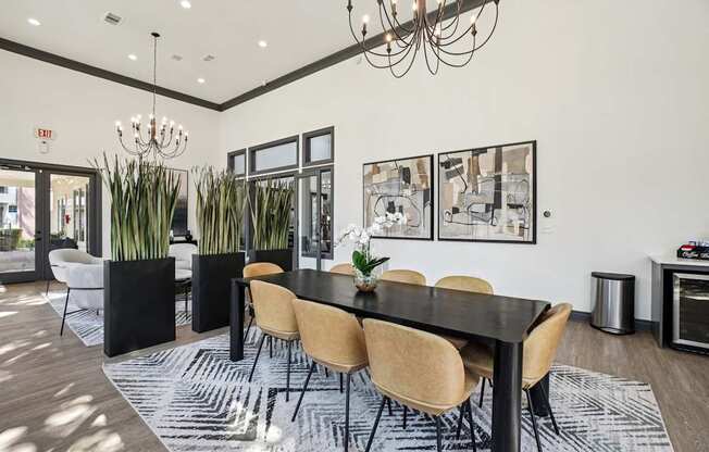 A black dining table with six chairs and a chandelier hangs above it.
