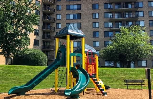 A playground with a green slide and a yellow and red tower.