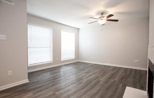 an empty living room with wood floors and a ceiling fan