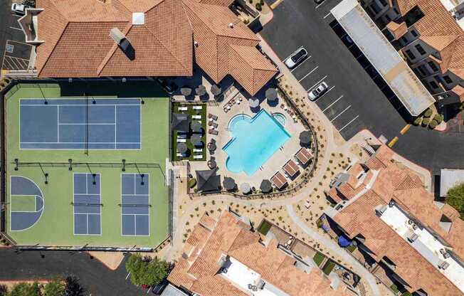 A tennis court with a pool and a building in the background.