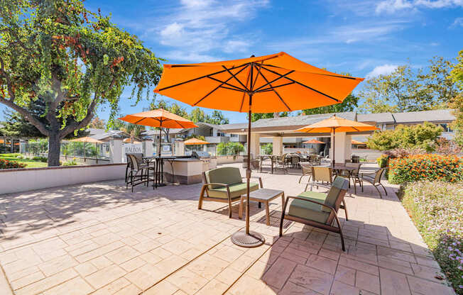 A patio with a table and chairs under an orange umbrella.