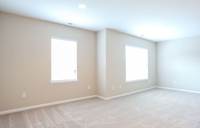 an empty room with two windows and a carpeted floor