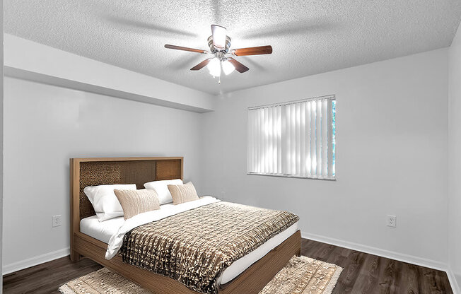 A bedroom with a bed, pillows, and a ceiling fan.