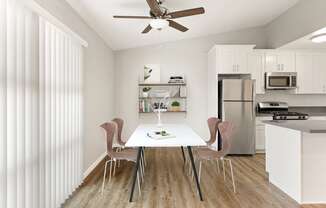 a dining room with a white table and chairs and a kitchen with stainless steel appliances