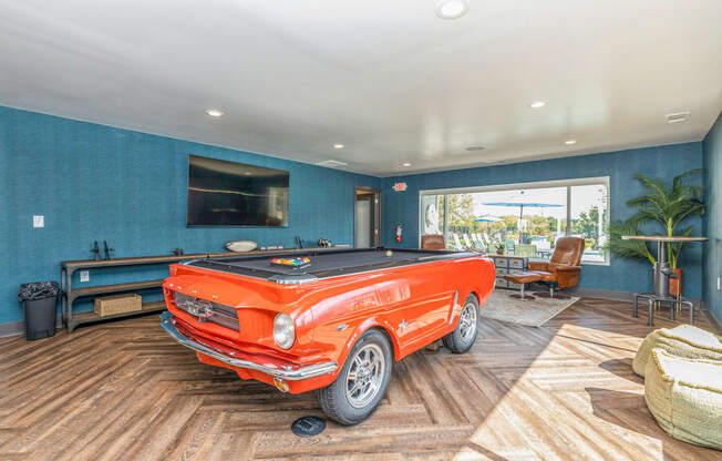 a pool table in a living room with a orange truck in the middle