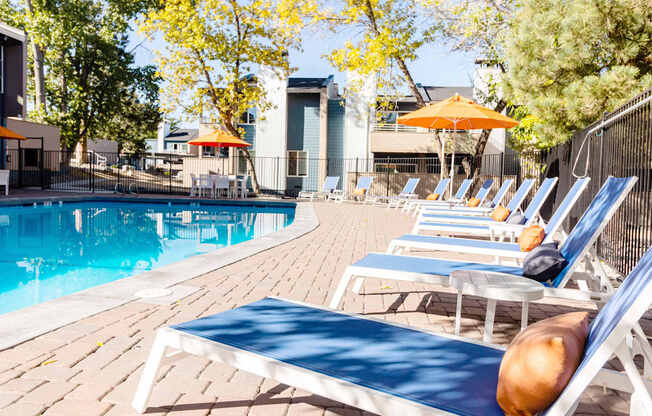 a pool with chairs and umbrellas at the resort on a sunny day