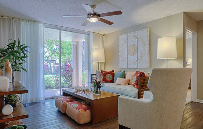 A living room with a couch, a chair, a table, and a ceiling fan.