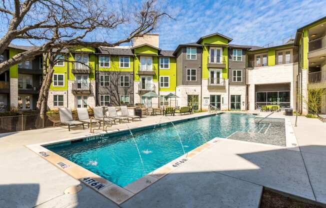 Pool with poolside lounge seating and umbrella shaded tables