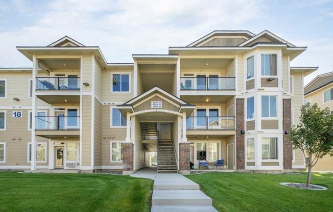 the view of an apartment building with a lawn and sidewalk