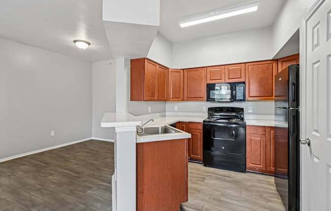 A kitchen with brown cabinets and black appliances.
