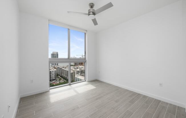 a bedroom with a large window and a ceiling fan