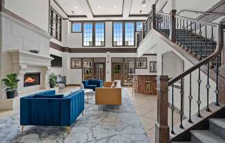 A large, open living room with a staircase and a fireplace.