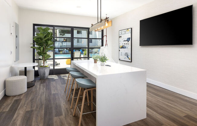 a kitchen with a long white counter top and a bar with stools at La Jolla Blue, San Diego, 92122