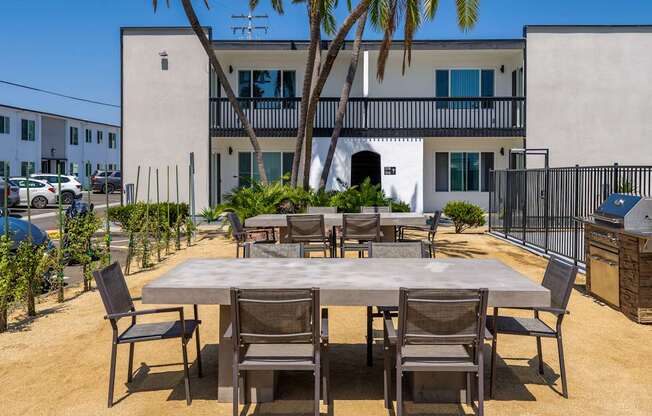 A table surrounded by chairs is in the middle of a courtyard.